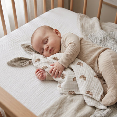 Bébé endormi avec son doudou oreilles lapin arc-en-ciel gris en coton mousseline