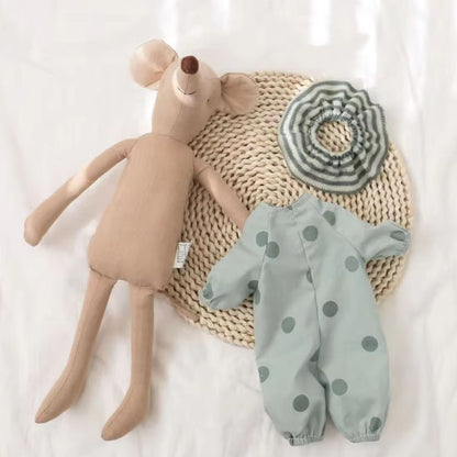 Doudou souris verte avec tenue amovible à pois posée sur natte en osier
