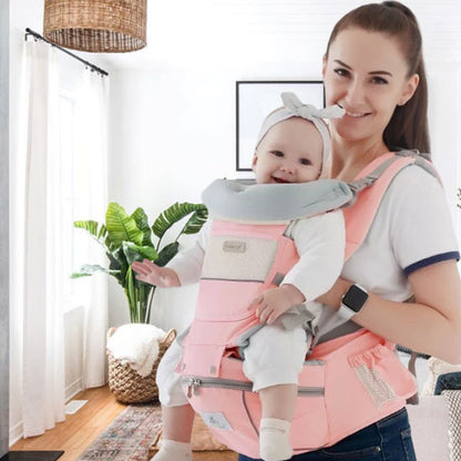 maman porte bebe par devant dans un porte bebe rose tout en souriant